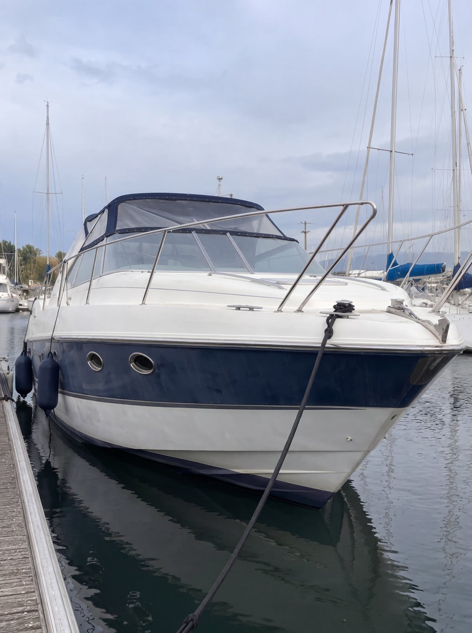 Motor yacht at its berth with a dull, oxidised blue hull and no reflection